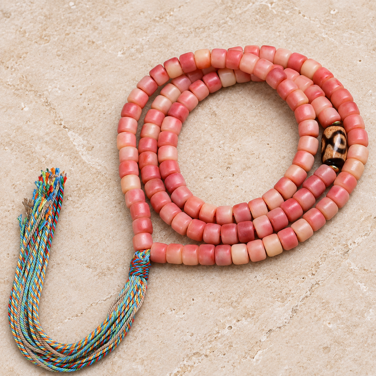 Pink and cream barrel bead mala with patterned accent and multicolor tassel, full product view.